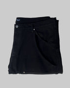 Folded black pants with a brand label on a white background