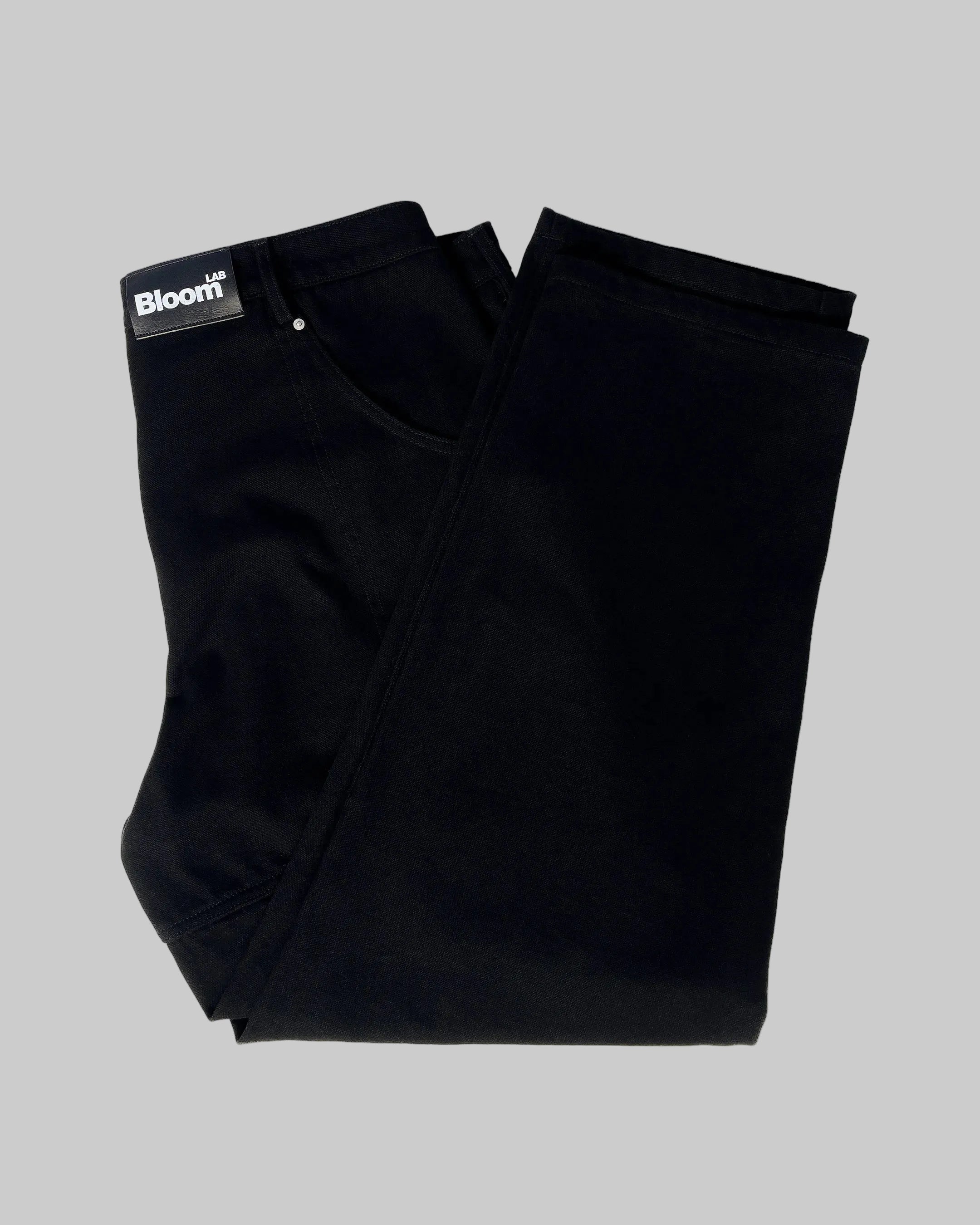 Folded black pants with a 'Bloom' label on a white background